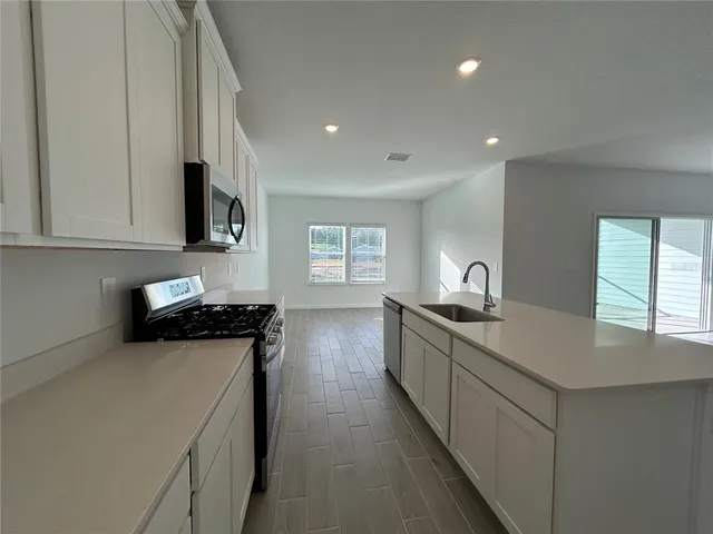 a kitchen with stainless steel appliances granite countertop a sink a stove top oven a counter space and cabinets