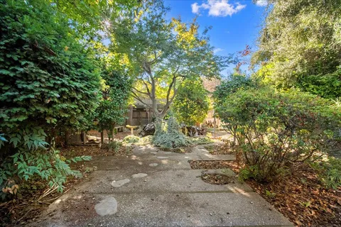 a backyard of a house with table and chairs a barbeque with a tree