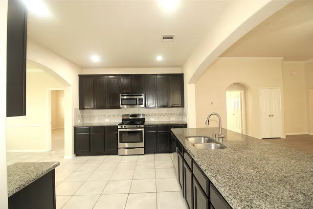 a large kitchen with granite countertop a sink and cabinets
