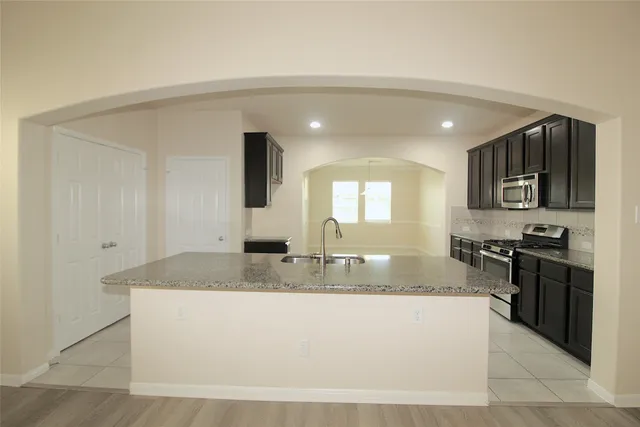 a large kitchen with kitchen island granite countertop a large counter top and stainless steel appliances