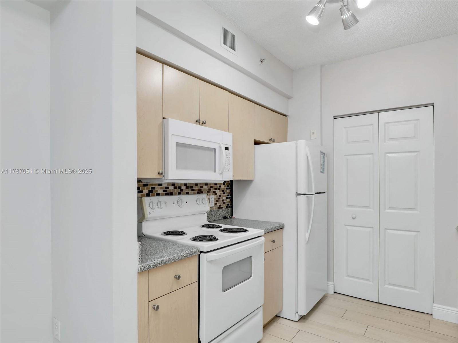 1235 Reserve Way, Unit 5107 Naples, FL 34105 - Photo 26 of 27 a kitchen with a white cabinets and white appliances