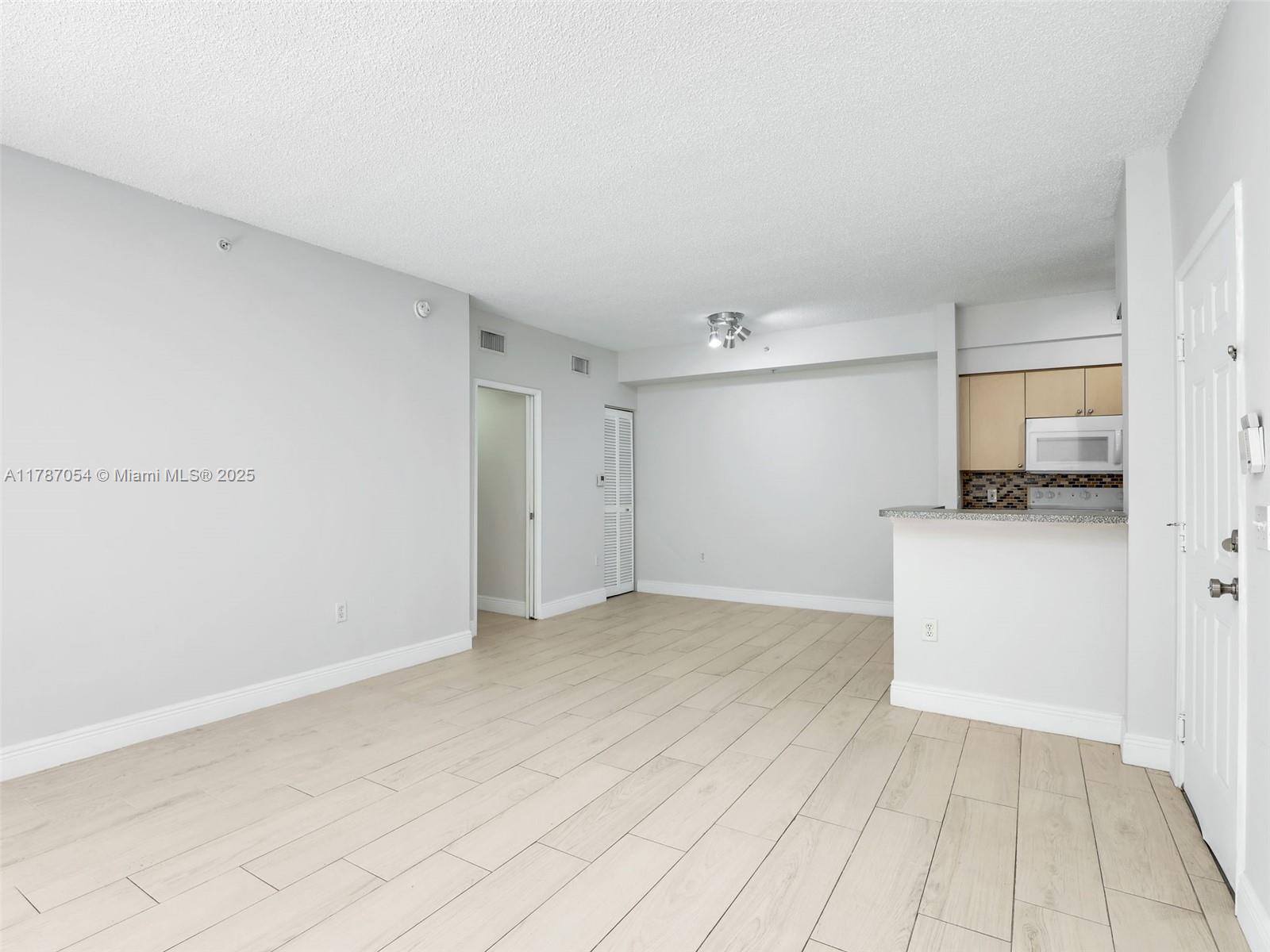 1235 Reserve Way, Unit 5107 Naples, FL 34105 - Photo 4 of 27 a view of empty room with wooden floor and cabinets