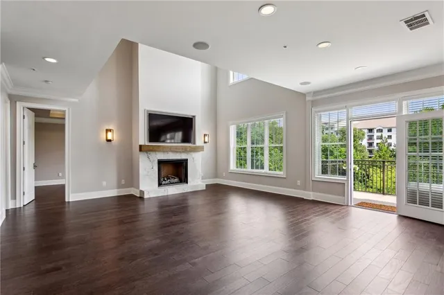 an empty room with wooden floor fireplace and windows