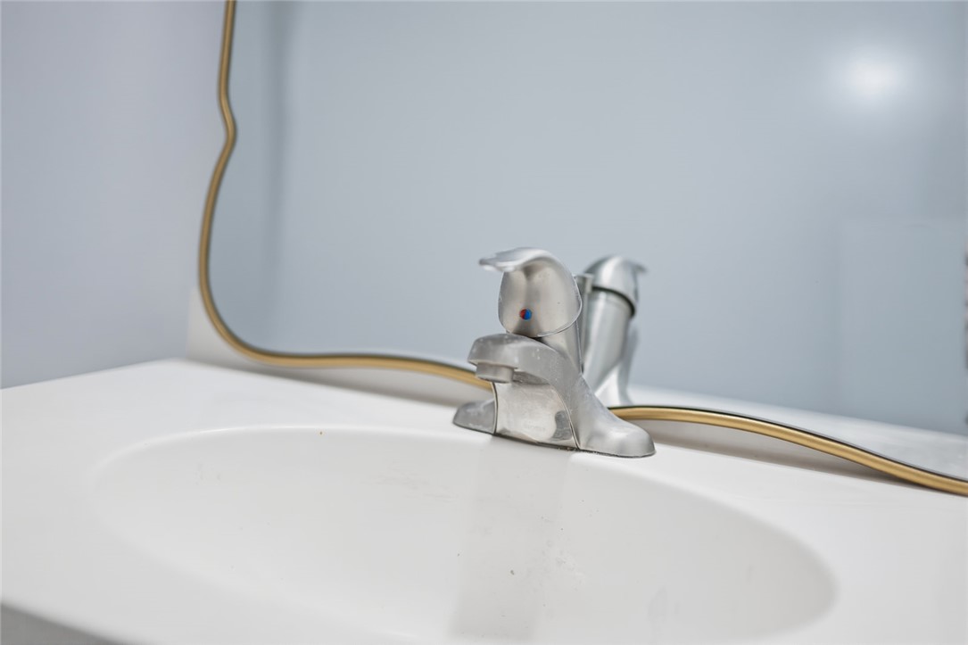 209 Cleveland Pike Road Westminster, SC 29693 - Photo 20 of 30 Modern sink with a unique curved mirror, adding both functionality and visual interest to the space.