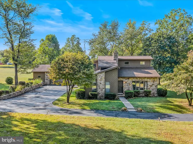 a view of a white house with a big yard and large trees