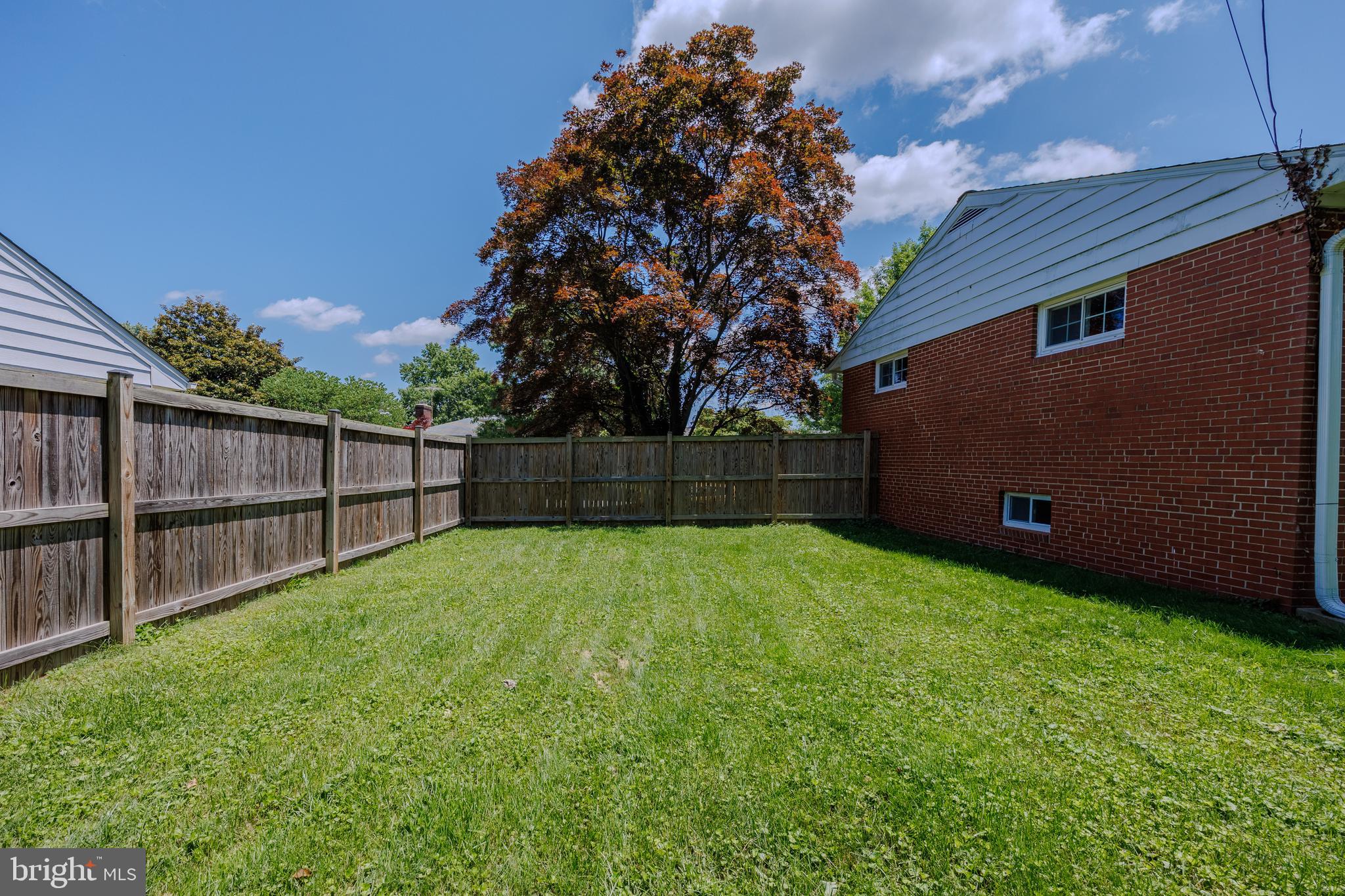 1305 Heather Hill Road Baltimore, MD 21239 - Photo 47 of 50 Backyard w/ grassy area, trees, and a wooden fence