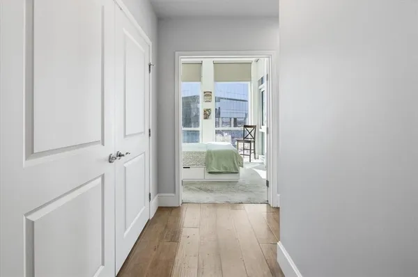 a view of a hallway with wooden floor and a bathroom