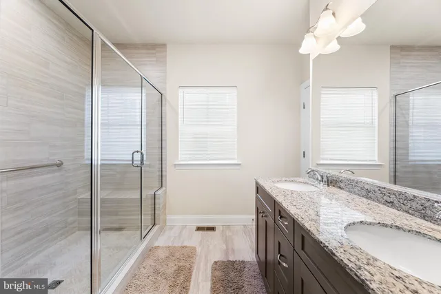a bathroom with a granite countertop sink a mirror and a shower