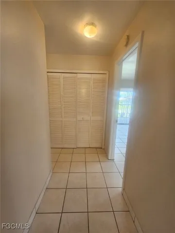 an empty room with chandelier fan and windows