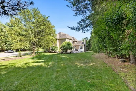 a view of a house with a big yard and large trees