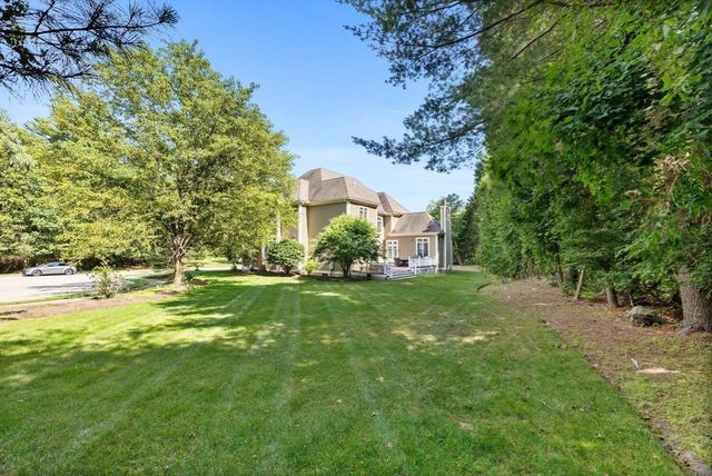 a view of a house with a big yard and large trees