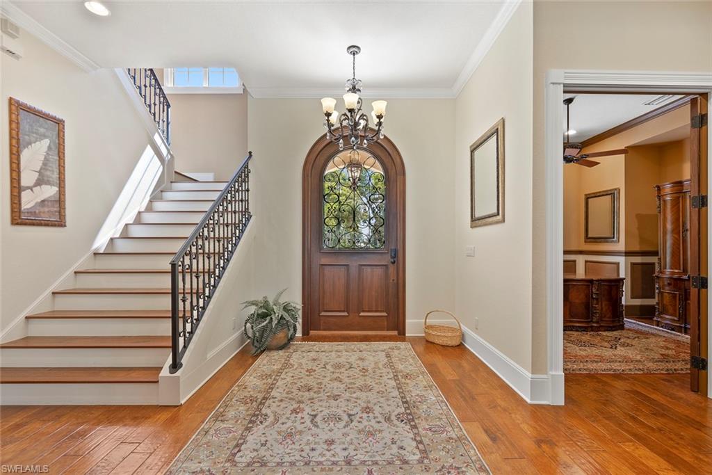 611 18th Avenue South Naples, FL 34102 - Photo 37 of 44 Foyer with crown molding, light wood-style flooring, a chandelier, ceiling fan, and stairway