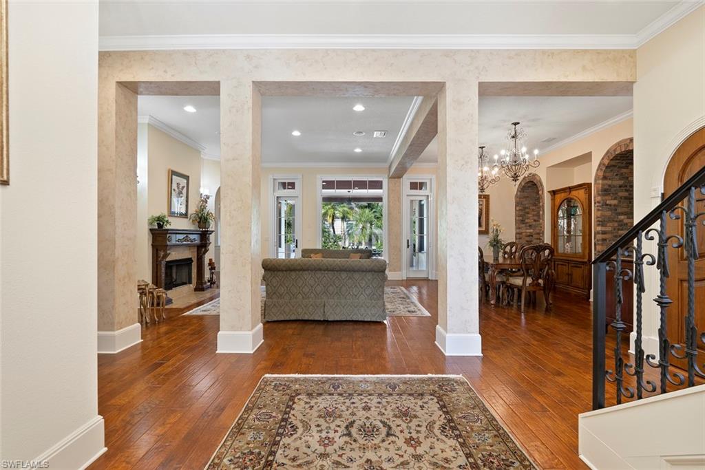 611 18th Avenue South Naples, FL 34102 - Photo 38 of 44 Foyer with stairs, dark wood-style flooring, a fireplace, crown molding, and recessed lighting