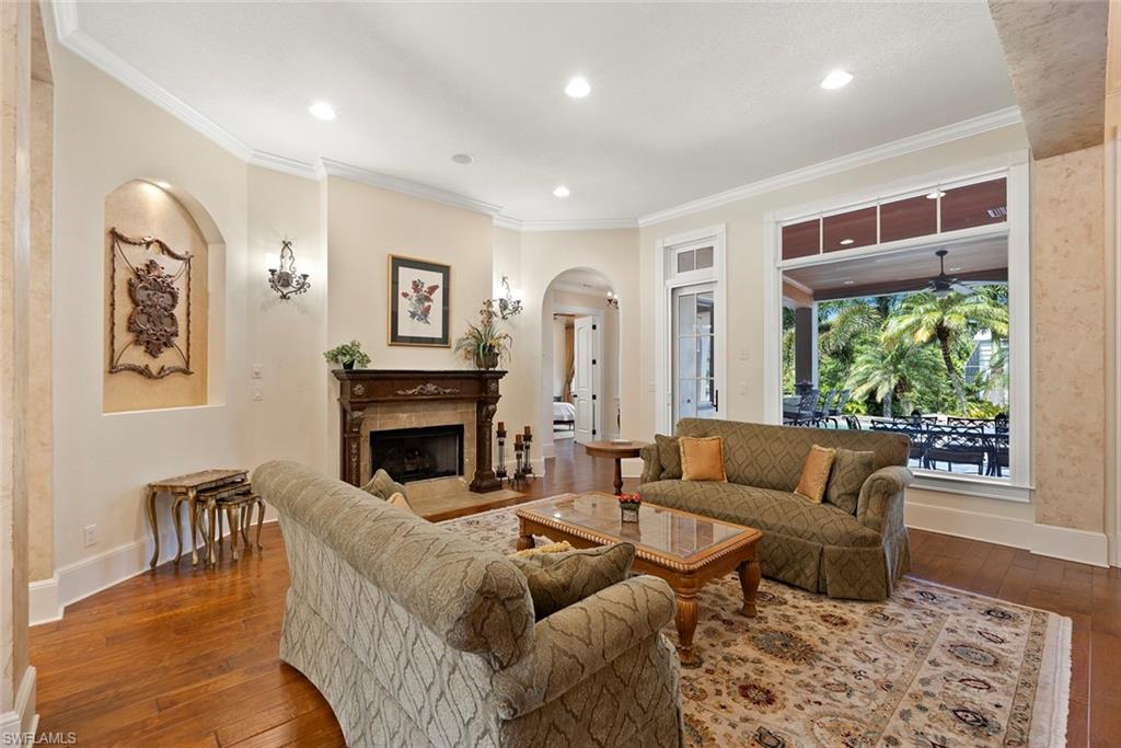 611 18th Avenue South Naples, FL 34102 - Photo 39 of 44 Living room with crown molding, a fireplace with flush hearth, arched walkways, dark wood-style floors, and recessed lighting