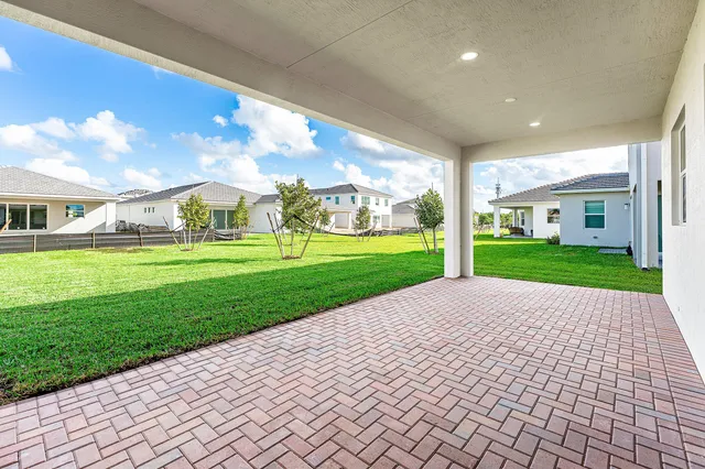 a view of a yard in front of a house with plants and large tree