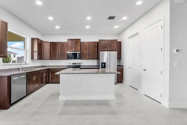 a kitchen with stainless steel appliances granite countertop a refrigerator a stove a sink and a oven