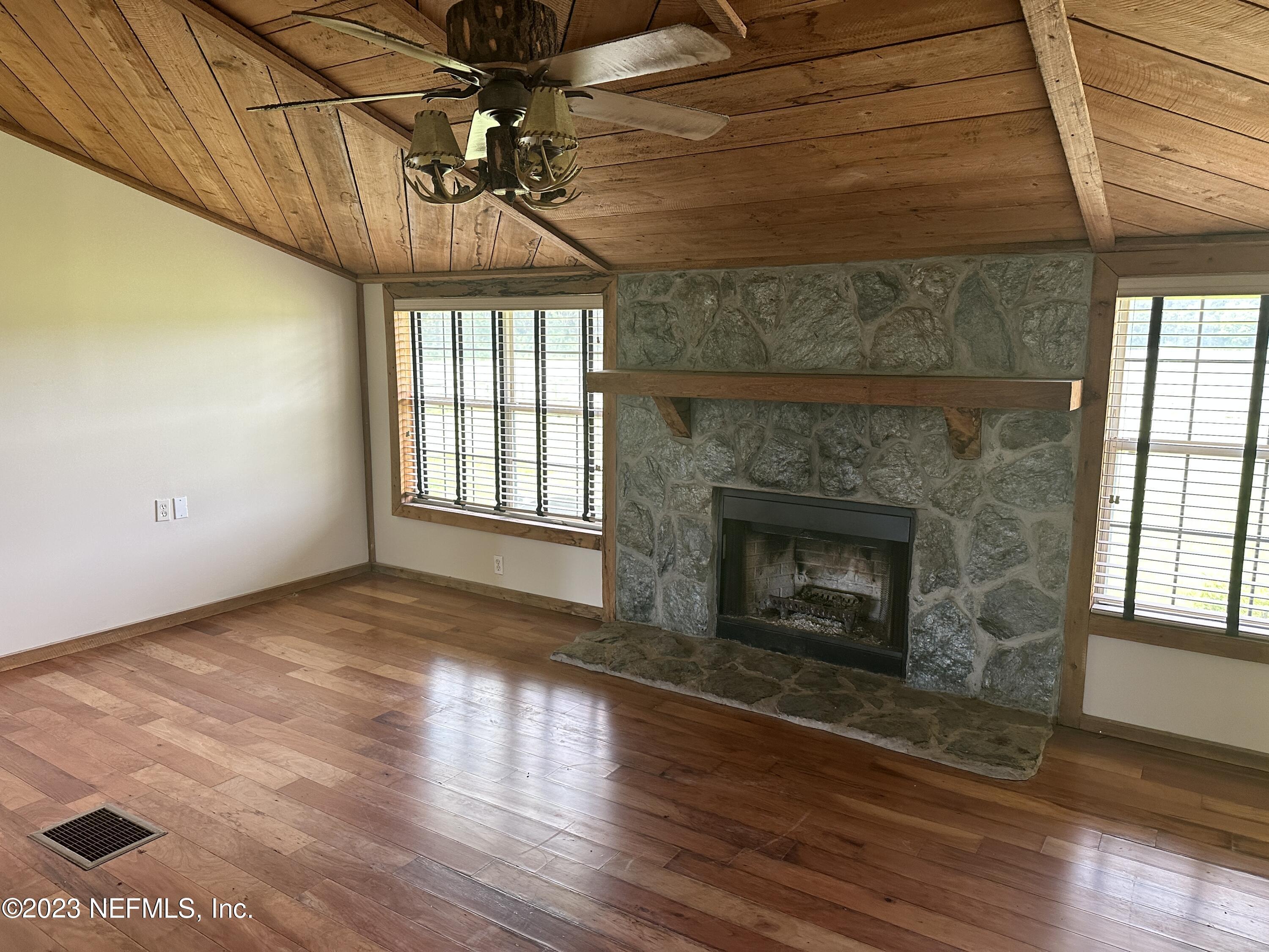 9465 Cowpen Branch Road, Unit A Hastings, FL 32145 - Photo 5 of 21 a view of an empty room with wooden floor fireplace and a window