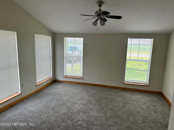an empty room with windows and fan