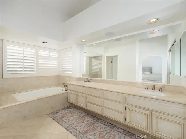 a spacious bathroom with double vanity a mirror a bathtub and a shower