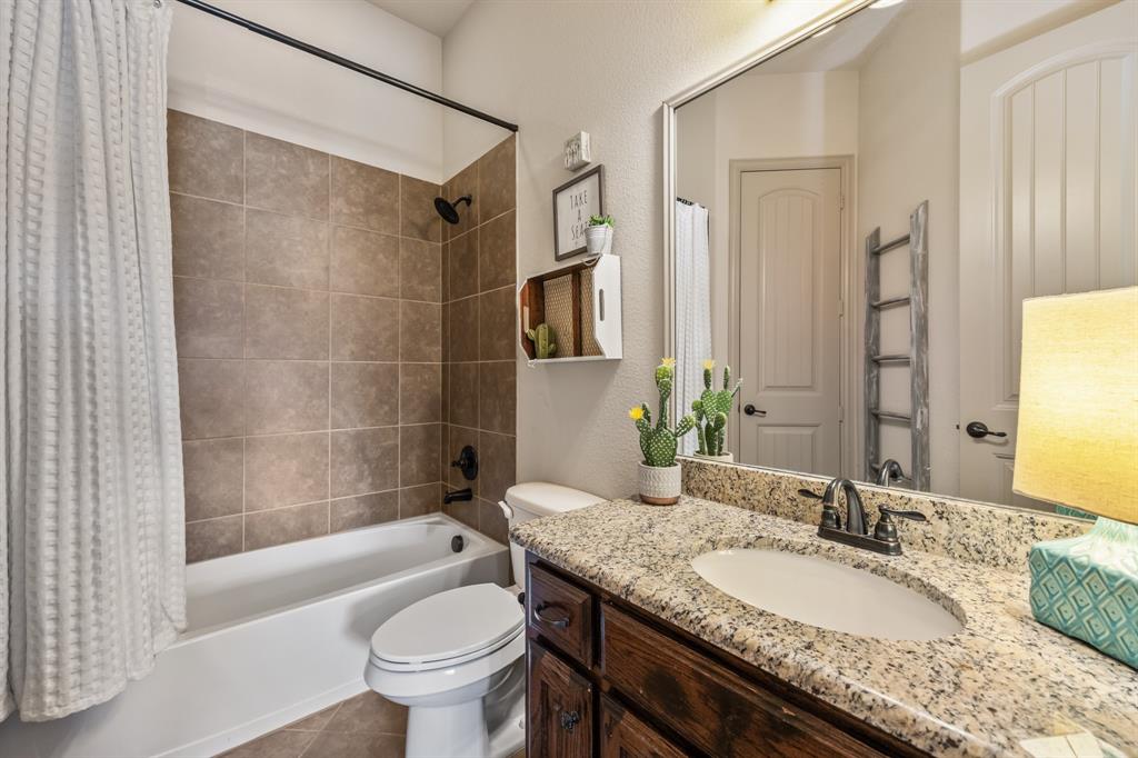 1206 Wedgewood Drive Forney, TX 75126 - Photo 21 of 40 a bathroom with a granite countertop sink a toilet a mirror a bathtub and shower
