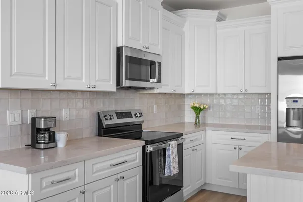 a kitchen with stainless steel appliances granite countertop white cabinets a stove a sink and dishwasher
