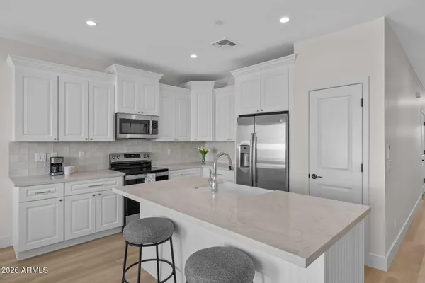 a kitchen with white cabinets a sink stove and refrigerator
