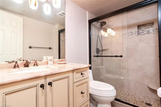 a bathroom with a sink a toilet a mirror and shower