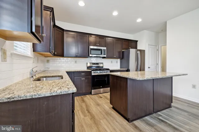 a kitchen with stainless steel appliances granite countertop wooden cabinets a refrigerator and a stove