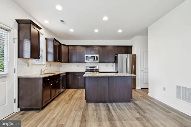 a large kitchen with stainless steel appliances kitchen island granite countertop wooden cabinets a sink and dishwasher