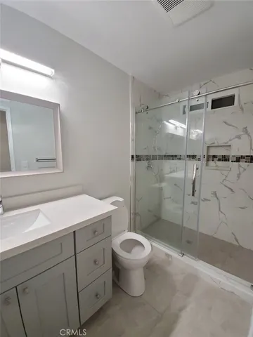 a bathroom with a shower sink vanity mirror and toilet