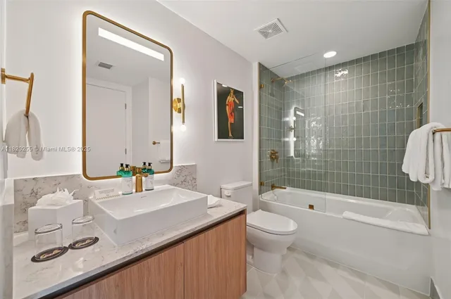 a bathroom with a granite countertop sink a toilet and shower