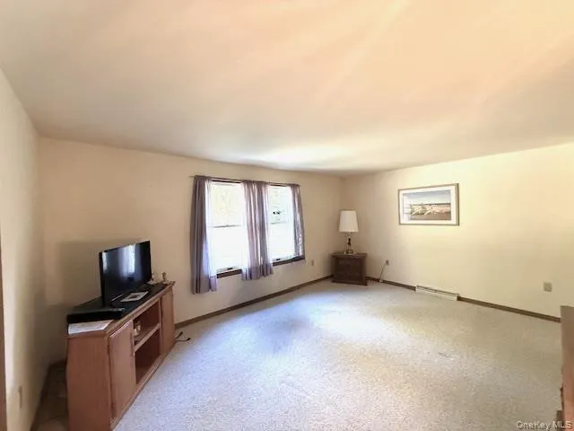 a view of an empty room with window and bathroom