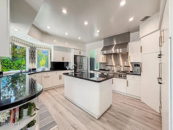 a large kitchen with stainless steel appliances granite countertop a lot of counter space and wooden floors