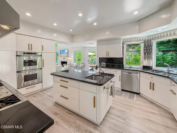 a kitchen with stainless steel appliances kitchen island granite countertop a sink stove and refrigerator