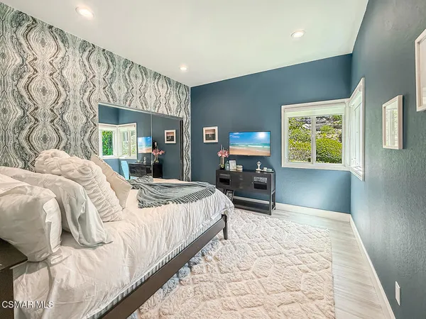 a bedroom with a large bed and a flat tv screen on dresser