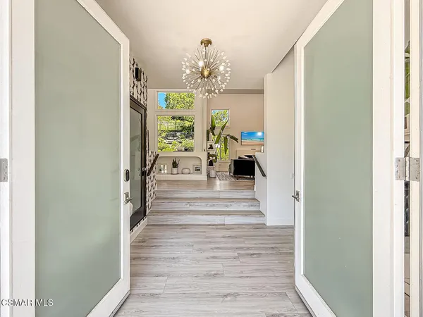a view of a hallway with wooden floor and chandelier