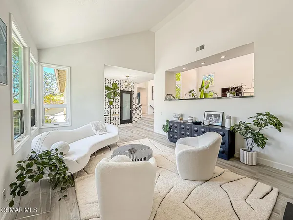 a living room with furniture potted plant and large window