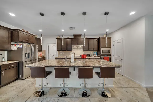 a kitchen with stainless steel appliances granite countertop a sink refrigerator and cabinets