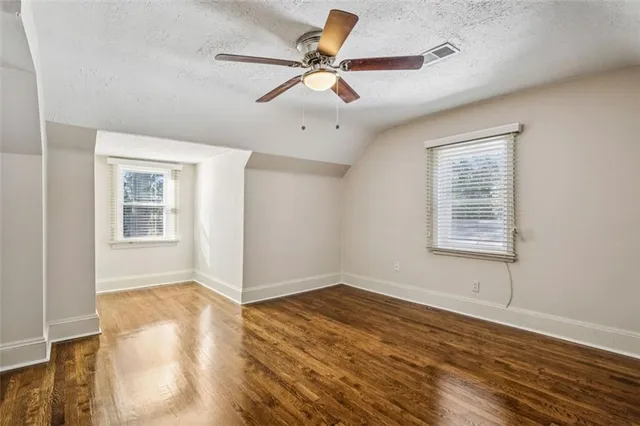 a view of an empty room with window and wooden floor