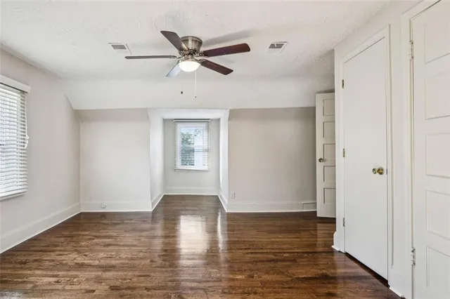 a view of empty room with wooden floor and fan