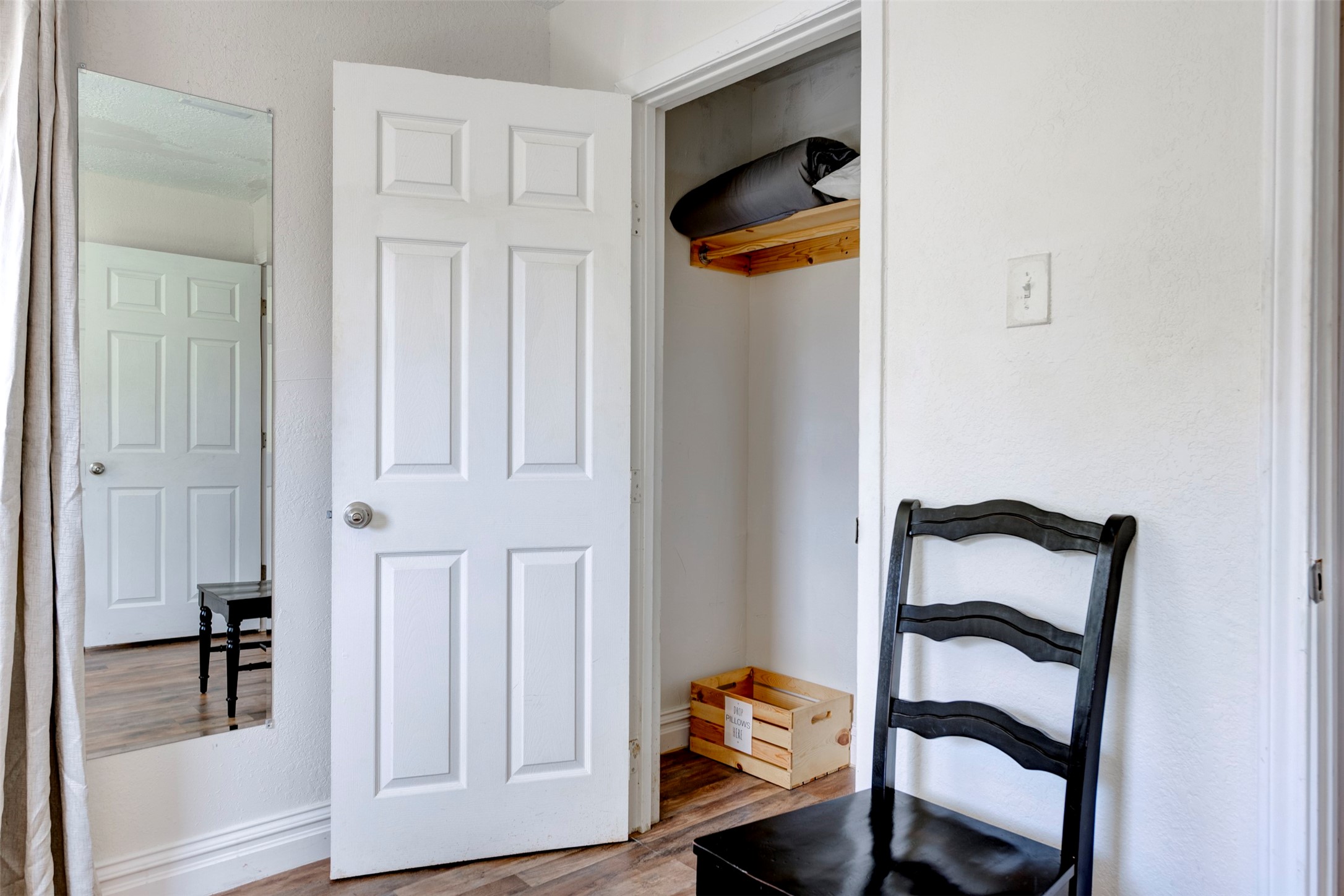 1121 Panama Street Houston, TX 77009 - Photo 19 of 35 Bedroom closet detail showing white six-panel door, natural wood upper shelf with hanging rod, and hardwood-style flooring throughout.