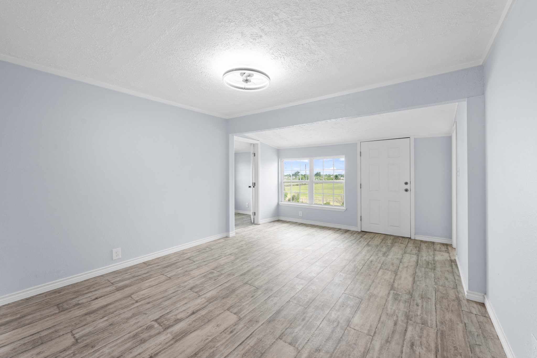 2534 Bastrop Angleton, TX 77515 - Photo 19 of 50 Spacious primary suite featuring updated wood-look flooring, soft neutral tones, and large windows that bring in abundant natural light and peaceful outdoor views. The flexible layout offers ample room for a sitting area or additional furnishings, creating a comfortable private retreat.