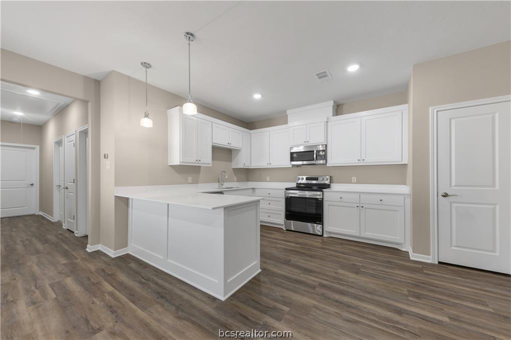 1249 Storm Row Lane Bryan, TX 77803 - Photo 7 of 20 a kitchen with a white stove cabinets and wooden floor