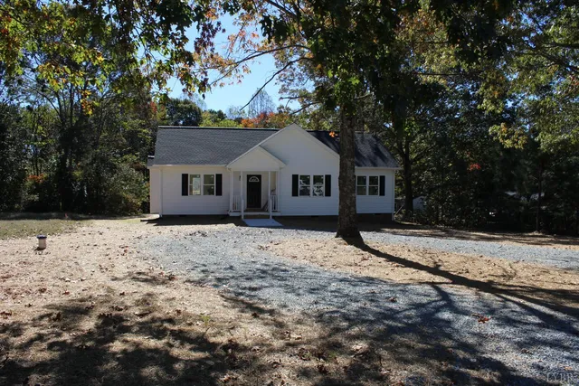 a front view of a house with a dirt yard and a large tree