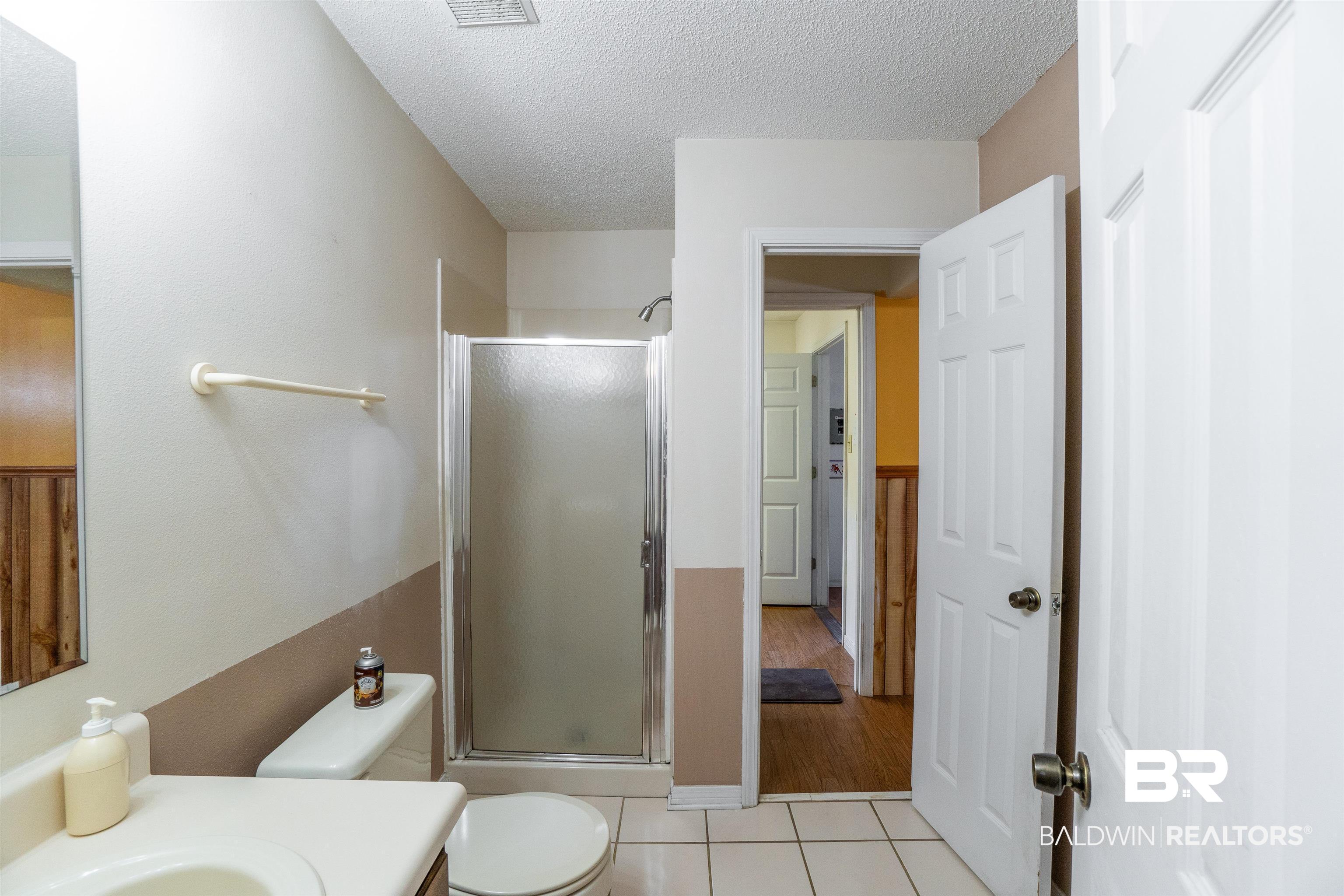 10349 Longview Drive West Foley, AL 36535 - Photo 27 of 35 Bathroom featuring a shower with door, vanity, tile patterned flooring, and a textured ceiling