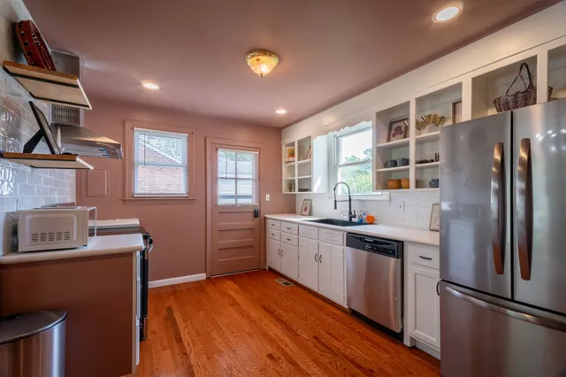 a kitchen with stainless steel appliances granite countertop a refrigerator a sink dishwasher a stove with wooden cabinets and floor