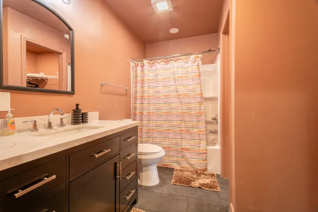 a bathroom with a granite countertop sink a toilet and a mirror