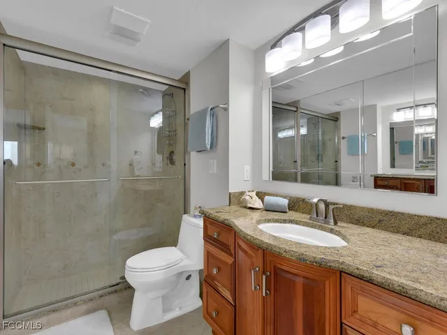 a bathroom with a granite countertop shower sink vanity mirror and toilet