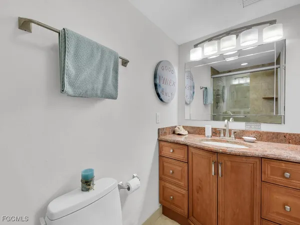 a bathroom with a granite countertop sink mirror and toilet