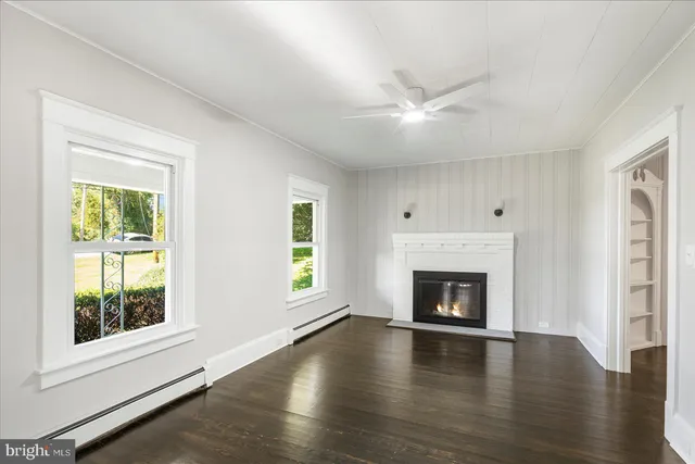 an empty room with fireplace wooden floor and windows